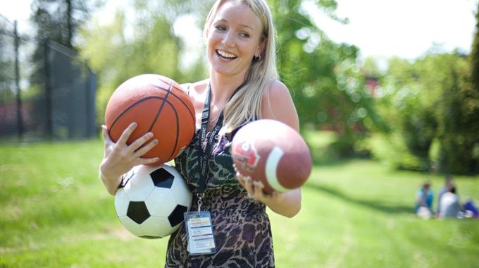 Woman holding a football, soccer ball and basketball