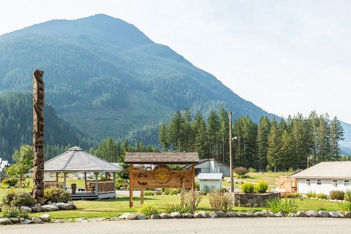 Mountain in background with park, Indigenous welcome post and wooden sign in foreground