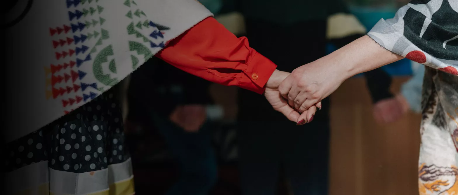 closeup of from behind of two people holding hands. 