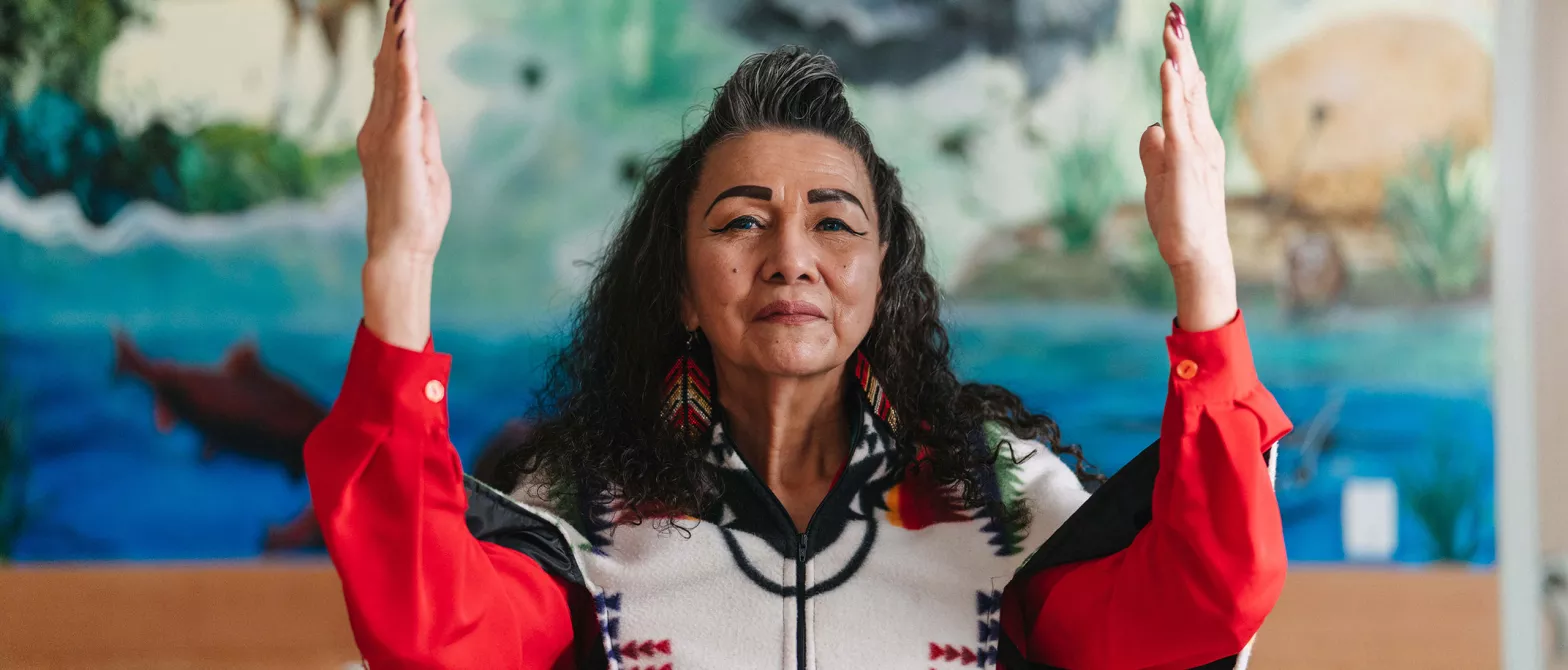 Indigenous elder woman with hands held up in gratitude