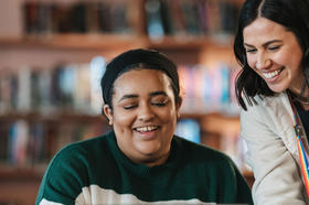 two women smiling and looking at something