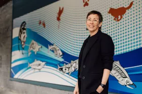 staff member standing in front of some Indigenous art at Red Fish