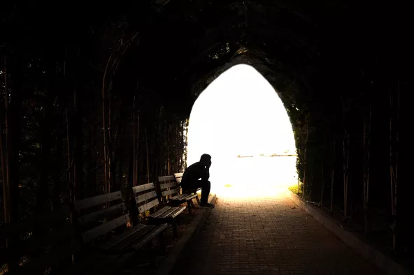 Person sitting on bench in dark tunnel