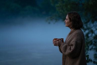 Woman gazing outwards at dusk while holding mug