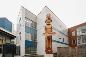 White building with a totem pole in front of it