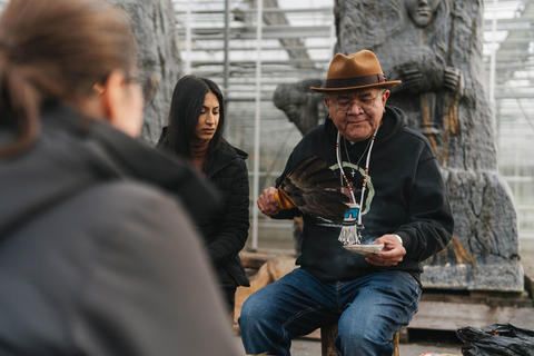 Indigenous elder smudging outdoors with a woman and man
