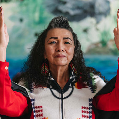Indigenous elder woman with hands held up in gratitude