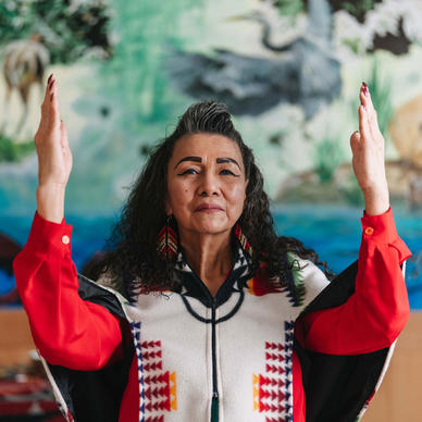 Indigenous elder woman with hands held up in gratitude