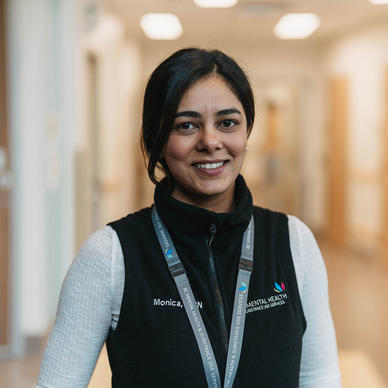 Young woman wearing a lanyard and vest smiles. 
